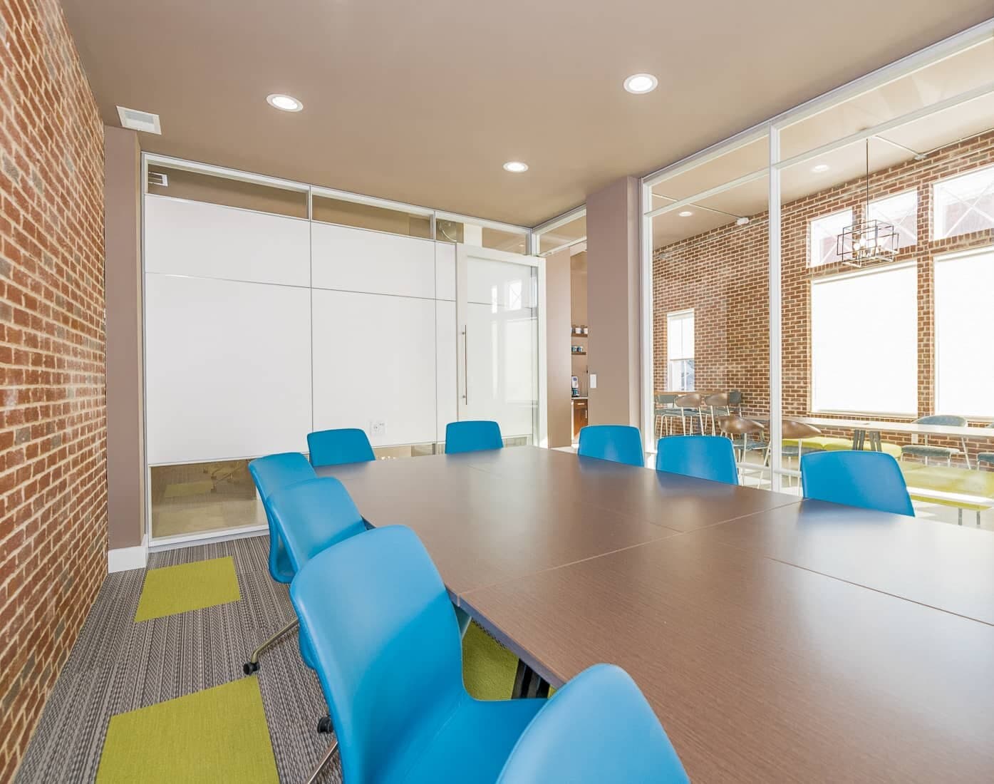 Conference room with long table, blue chairs, and wall monitor