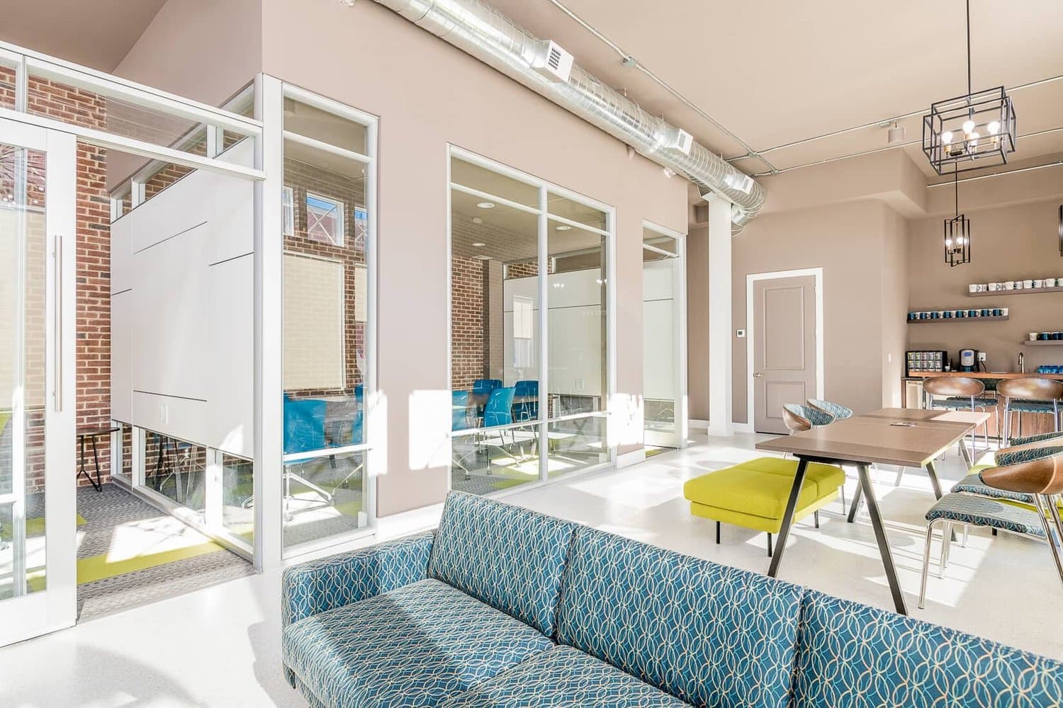 Lounge with patterned sofa beside glass-walled conference rooms