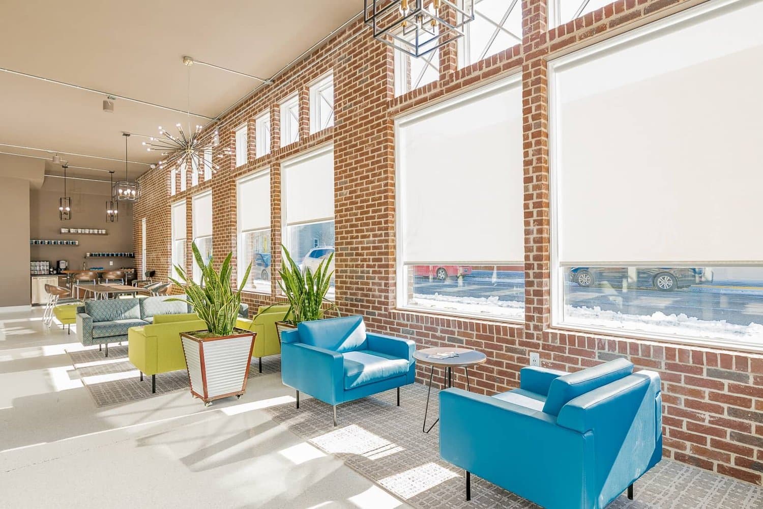 Open seating area with teal lounge chairs by large windows