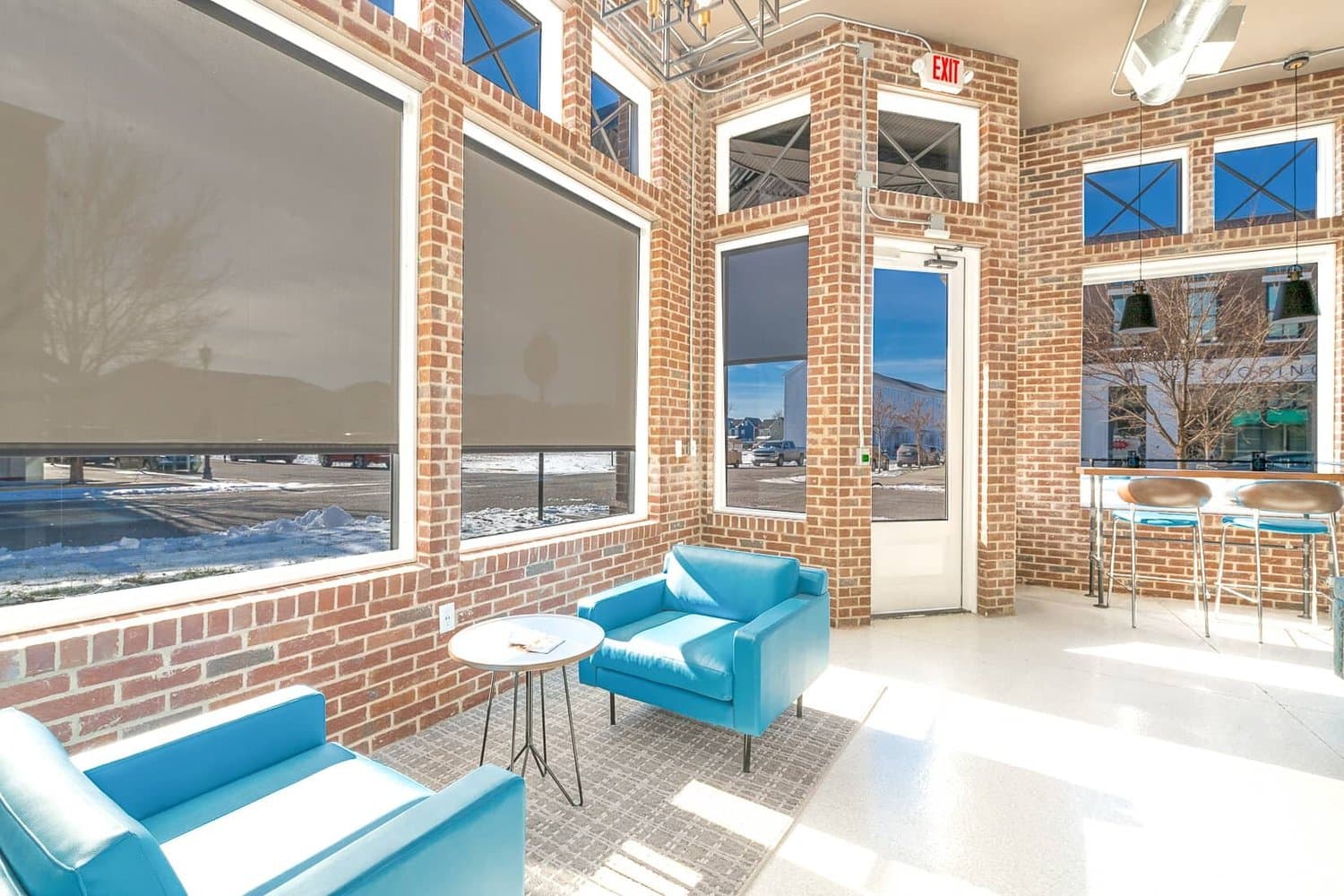 Teal lounge chairs beside tall windows